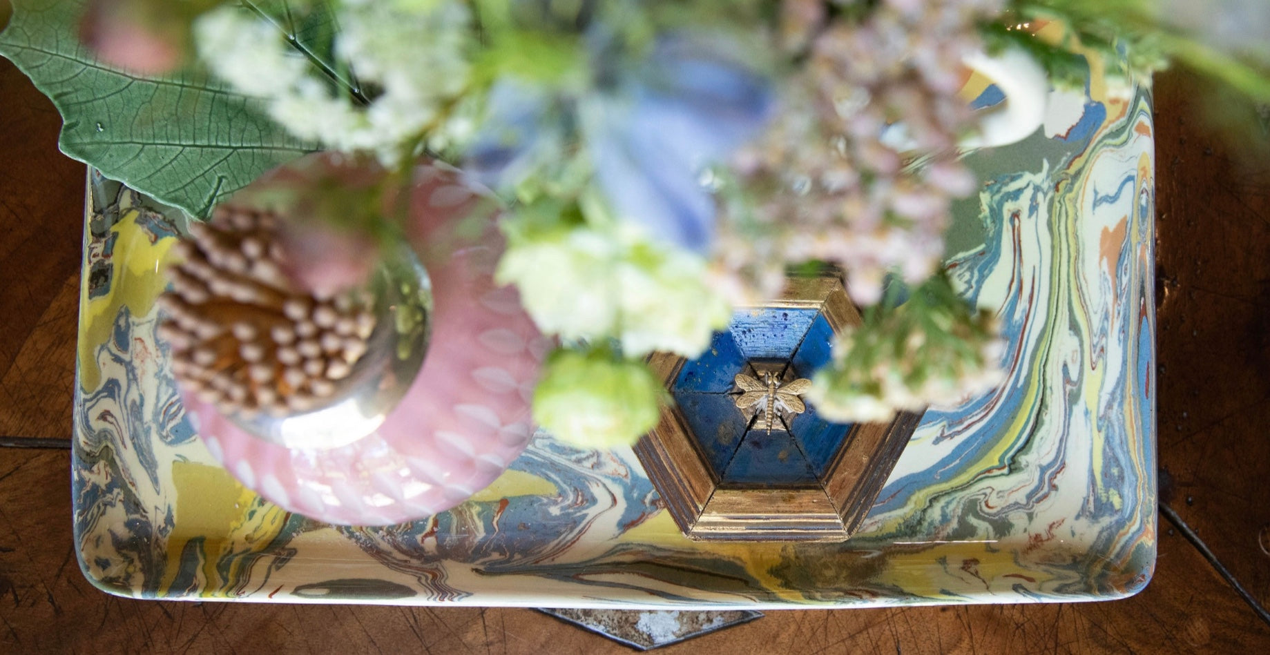 Decorative box with floral and shell design on a wooden surface