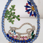 Decorative peacock brooch with colorful gemstones on a white background