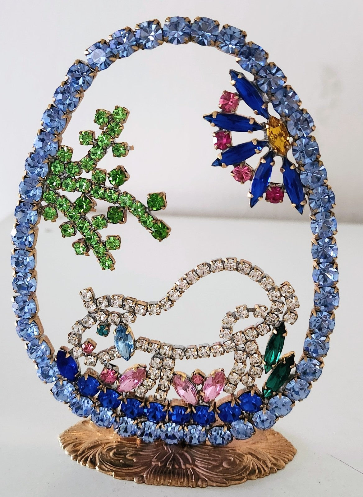 Decorative peacock brooch with colorful gemstones on a white background